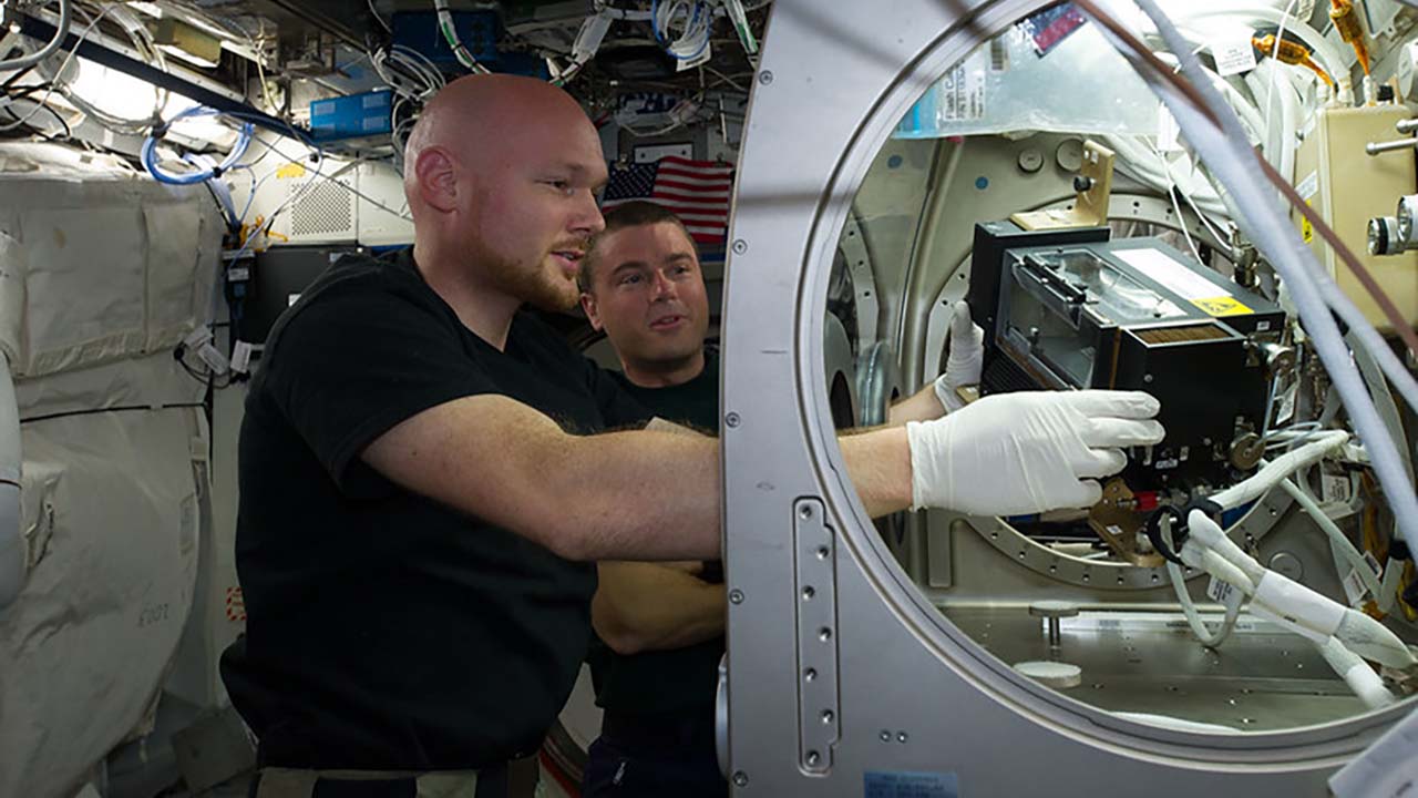 ESA astronaut Alexander Gerst and NASA astronaut Reid Wiseman work in the Microgravity Science Glovebox onboard the ISS