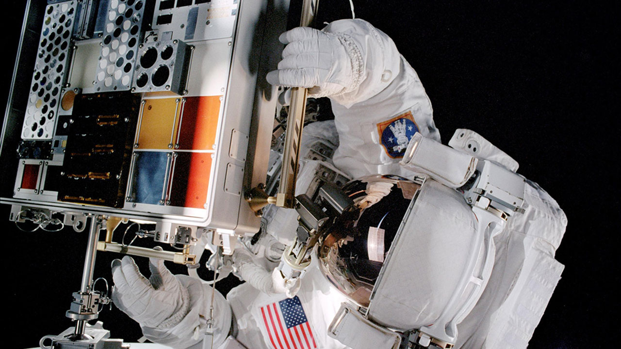 An astronaut installs a Materials International Space Station Experiment (MISSE) facility on the exterior of the ISS during a spacewalk in 2001.