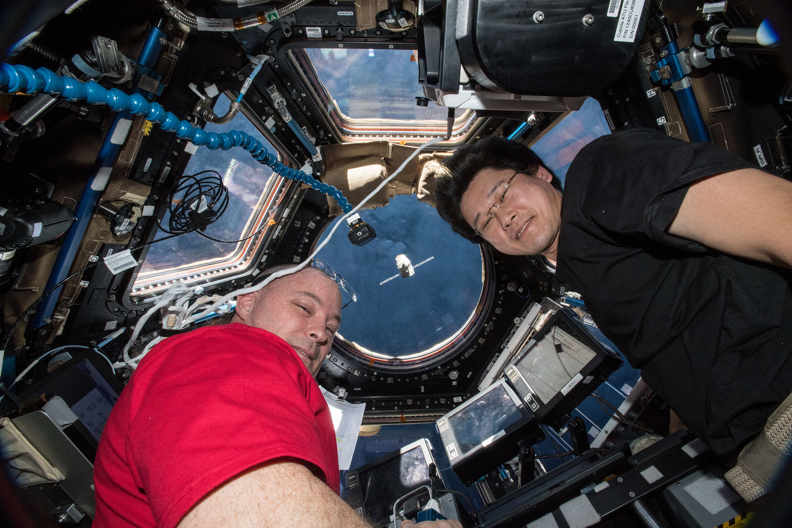 Astronauts Scott Tingle (left) and Norishige Kanai watch the SpaceX Dragon cargo craft arrive from inside the seven windowed Cupola moments before capturing it with the Canadarm2 robotic arm.