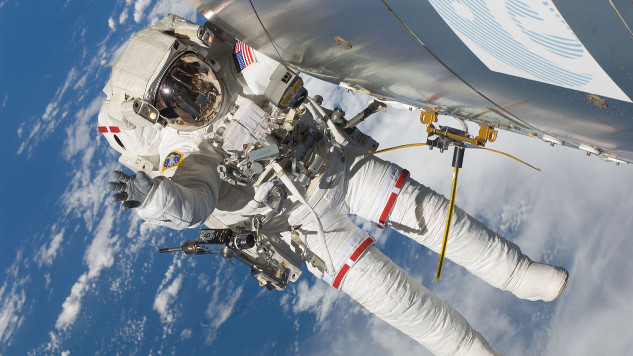 Astronaut Randolph Bresnik seen during Atlantis EVA 2 on November 21, 2009, with the unfurled AIS antenna, attached to Columbus for use in experimental tracking of VHF signals of ships at sea.