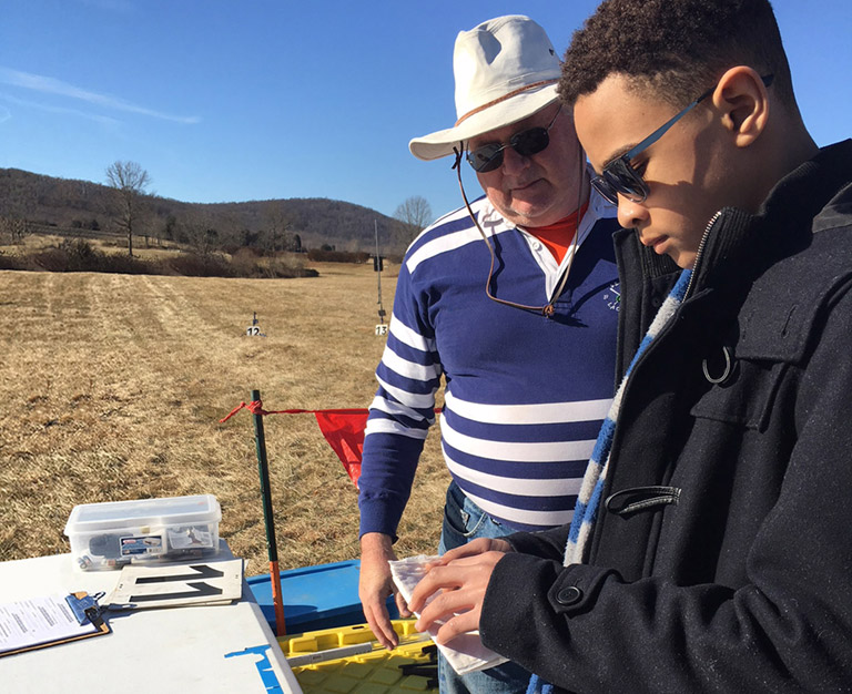 Desmen assembles a model rocket powered by an ESTES engine with a member of Northern Virginian Association of Rocketry (NOVAAR) looking on.