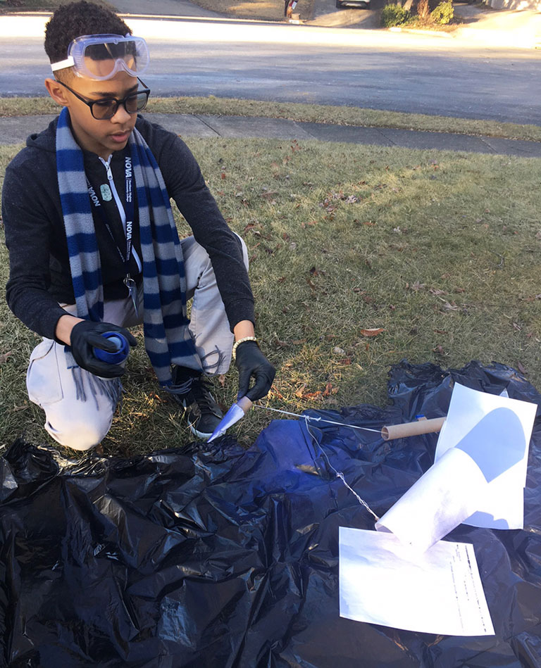 Desmen prepares to attach a parachute and nose cone to one of his model rockets.