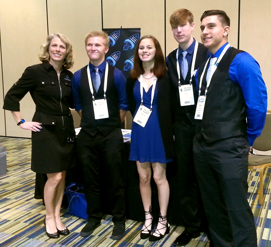 At the Project Lead the Way conference, Devin (right) poses with fellow engineering students and Michelle Lucas (left), founder and president of Higher Orbits.