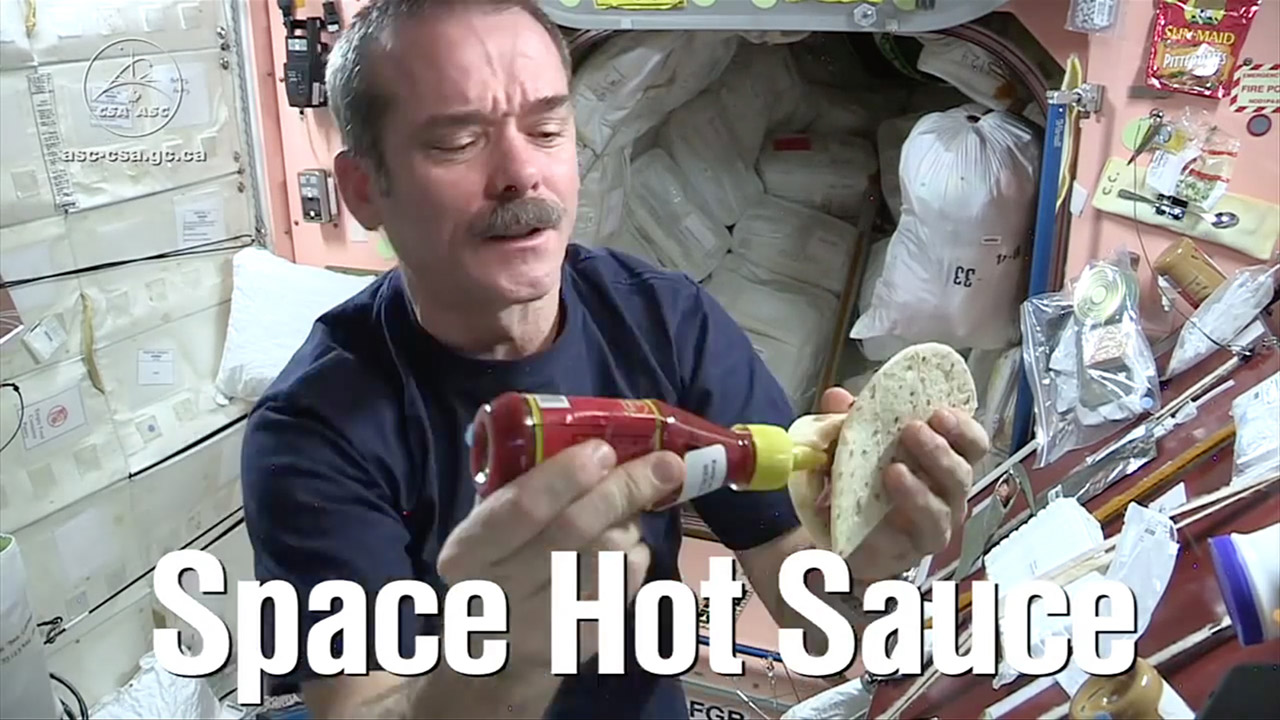 Canadian astronaut Chris Hadfield adds hot sauce as he prepares a burrito on the International Space Station.