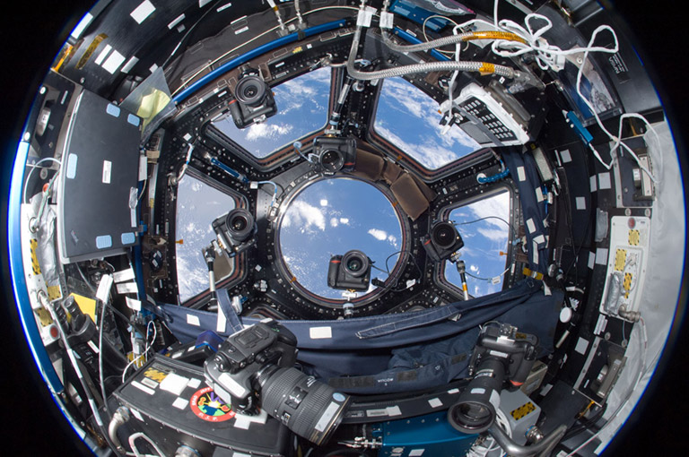 There are a lot of cameras in the Cupola! Some are handheld by astronauts and some are anchored with articulating arms. Usually their lenses are pointing out the window toward Earth, but some of them are turned inward.