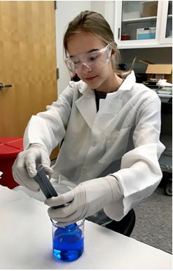 Kaitlyn Twesme prepares an inorganic chemical solution in the lab in preparation for their crystallization experiment.