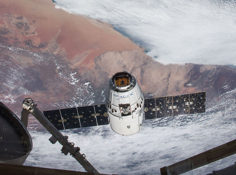 On April 4, 2018, the SpaceX Dragon resupply ship approached the International Space Station to be captured by the robotic arm. The southern coast of Namibia is visible behind it. NASA astronaut Ricky Arnold took this picture and tweeted, Welcome @SpaceX 14 packed with science and hopefully a few goodies for us too!