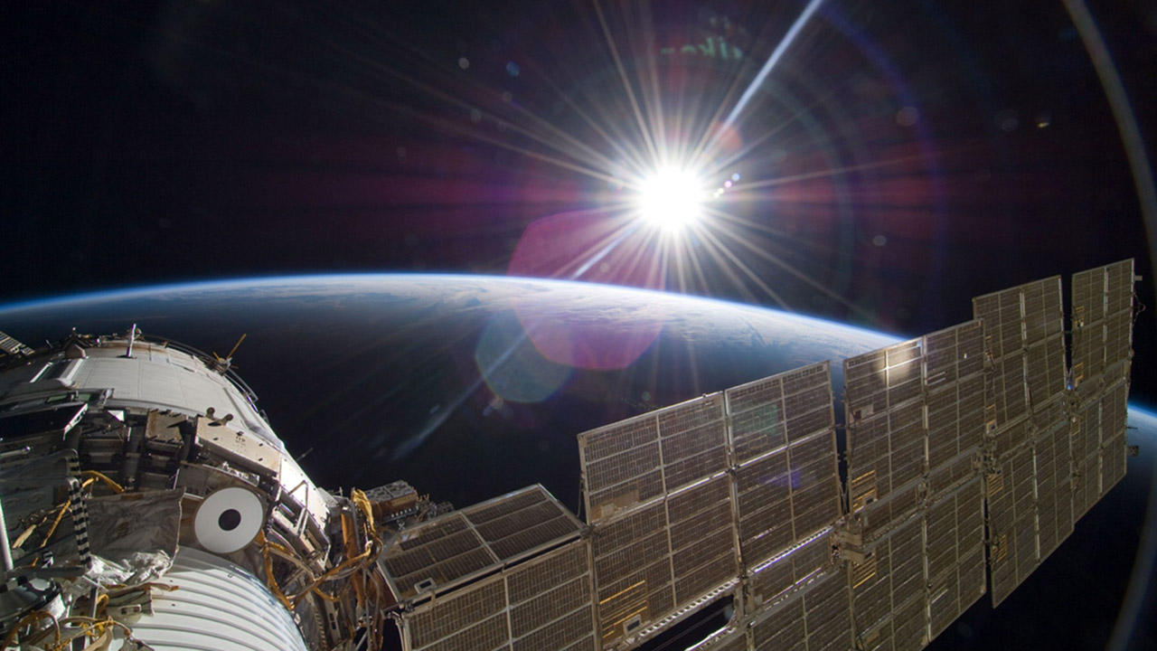 The bright sun greets the International Space Station and the Earth below.