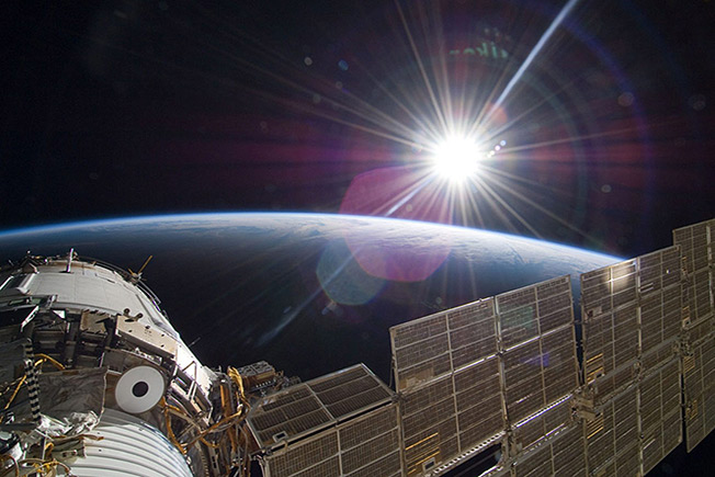 The bright sun greets the International Space Station and the Earth below.