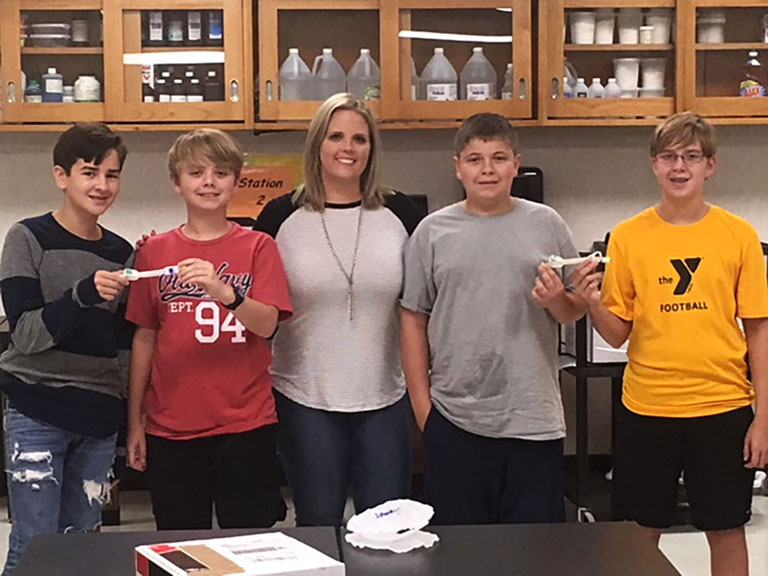 The students and their teacher display the tube that the got back from space and their control tube that stayed on the ground. Left to right: Blaine Bailes, Timothy Layne Kotzur, Teacher Mrs. Jamie Morton, Dominick Trostle, James Link.