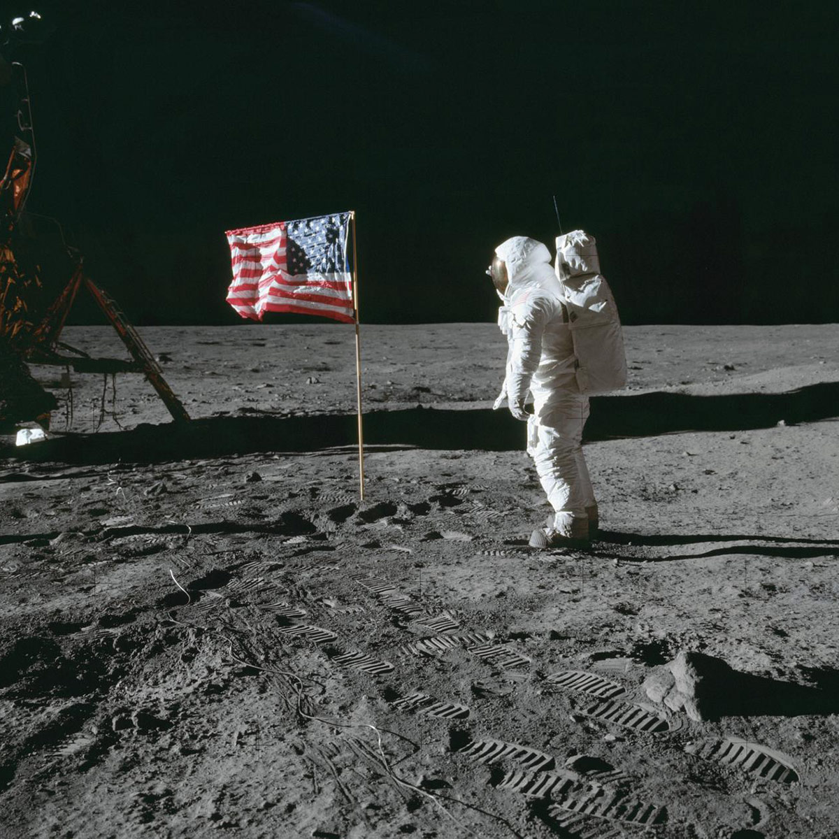 AS11 40 5874 (20 July 1969) Astronaut Edwin E. Aldrin Jr., lunar module pilot of the first lunar landing mission, poses for a photograph beside the deployed United States flag during Apollo 11 extravehicular activity (EVA) on the lunar surface. The Lunar Module (LM) is on the left, and the footprints of the astronauts are clearly visible in the soil of the moon. Astronaut Neil A. Armstrong, commander, took this picture with a 70mm Hasselblad lunar surface camera. While astronauts Armstrong and Aldrin descended in the LM the Eagle to explore the Sea of Tranquility region of the moon, astronaut Michael Collins, command module pilot, remained with the Command and Service Modules (CSM) Columbia in lunar orbit.