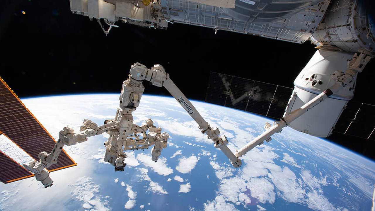 iss059e061425 (May 13, 2019) The Canadarm2 robotic arm with its robotic hand, also known as Dextre, attached for fine tuned robotics work extends across the frame as the International Space Station orbited 256 miles above the Atlantic Ocean. The SpaceX Dragon resupply ship is pictured at right berthed to the Harmony module.