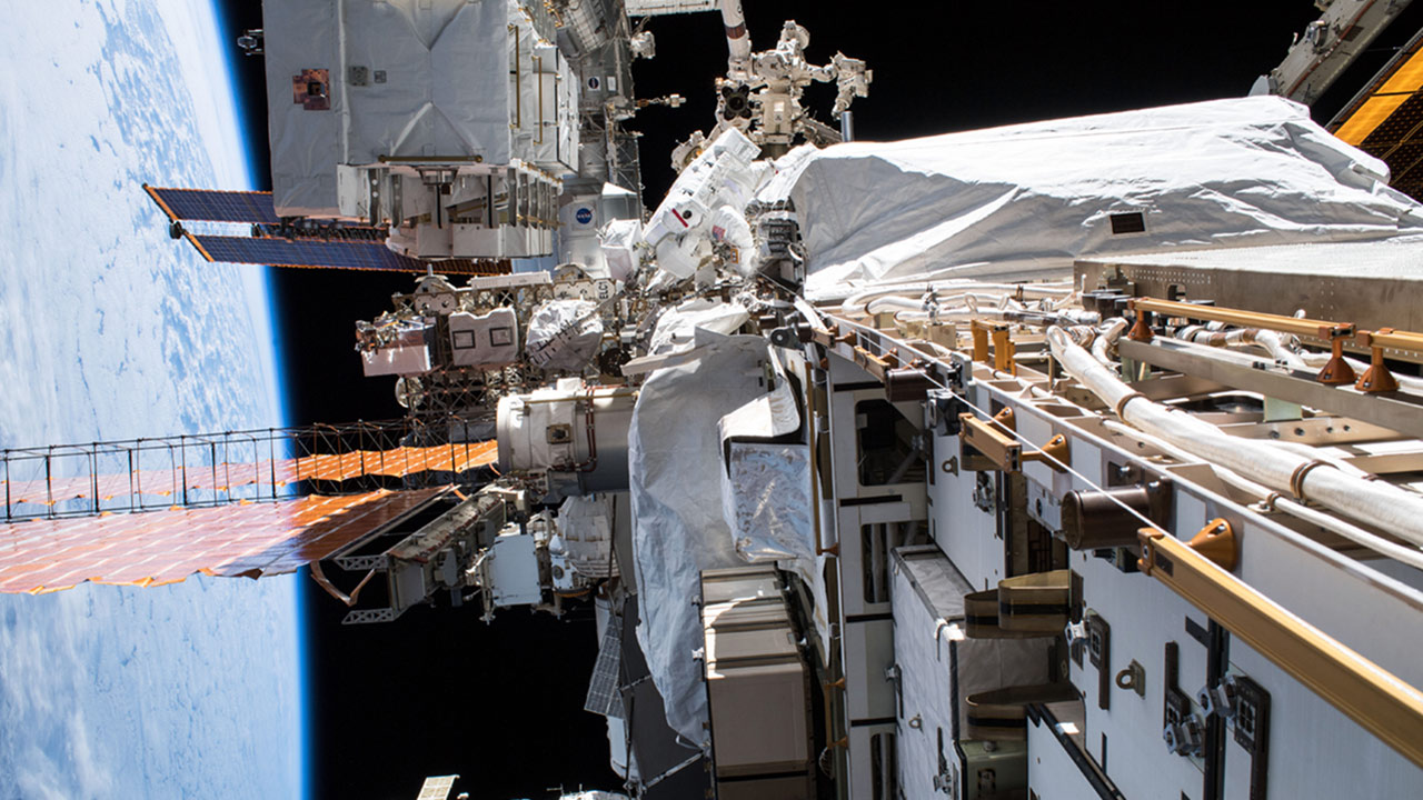 NASA astronaut Christina Koch (top center) conducts a spacewalk at the Port 6 (P6) truss structure work site to upgrade International Space Station power systems.