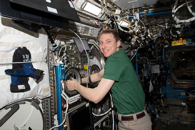NASA astronaut Woody Hoburg works on the graphene aerogel experiment in the microgravity science glovebox on station.