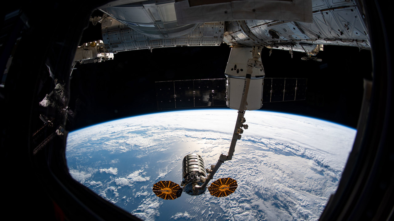 iss060e022993 (Aug. 6, 2019) The Cygnus resupply spacecraft from Northrop Grumman is shown grappled by the Canadarm2 robotic arm following its detachment from the Unity module and just before release. Behind the robotic arm, the SpaceX Dragon is seen still attached to the Unity module of the International Space Station.