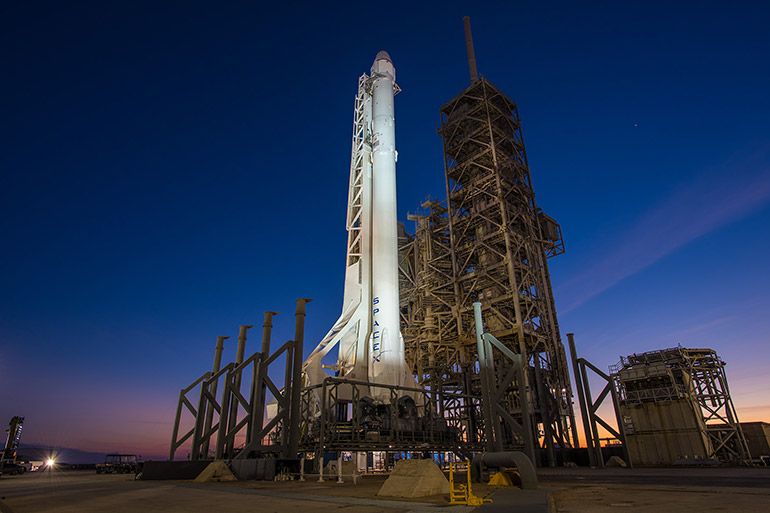 A SpaceX Falcon rocket fitted with a Dragon capsule stands ready to launch at Kennedy Space Center Launch Complex 39A.