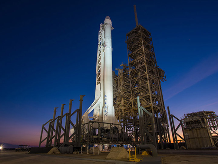 A SpaceX Falcon rocket fitted with a Dragon capsule stands ready to launch at Kennedy Space Center Launch Complex 39A.