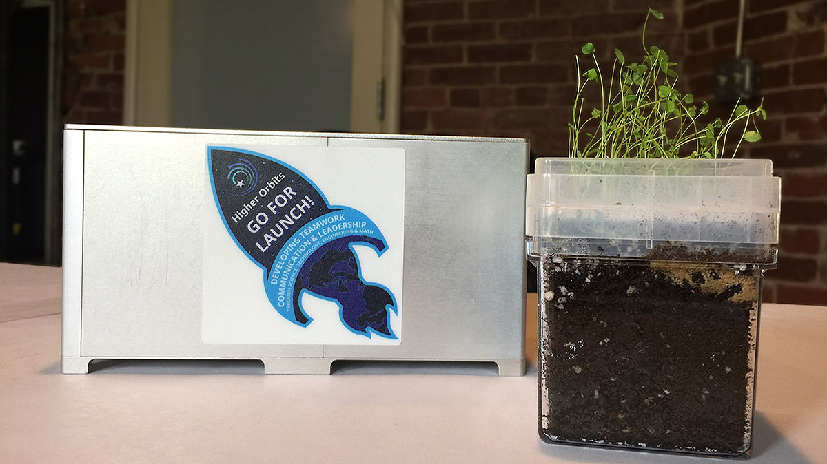 The container of microclover and moist soil fit snugly into a 10x10x20 cm metal box for installation in a Tangolab on the ISS. The plants emerge through small holes in a 3D printed plastic lid that holds the soil in place.