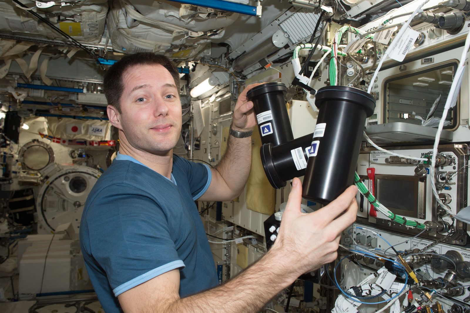 Crew member Thomas Pesquet removing the Protein Crystallization Facility hardware from the incubator on the ISS for a crystallization investigation by Merck & Co.