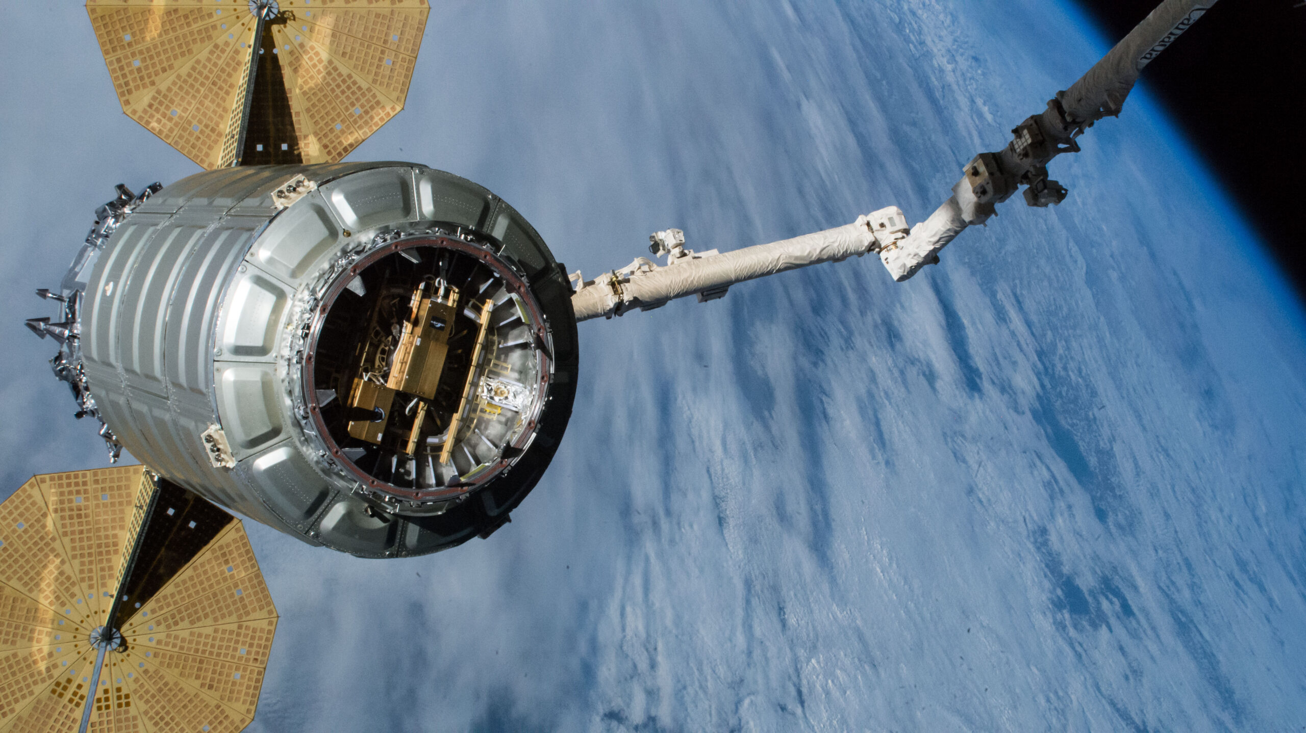 A Northrop Grumman Cygnus cargo craft pictured in the grips of the Canadarm2 robotic arm as the International Space Station orbits over the Pacific Ocean.