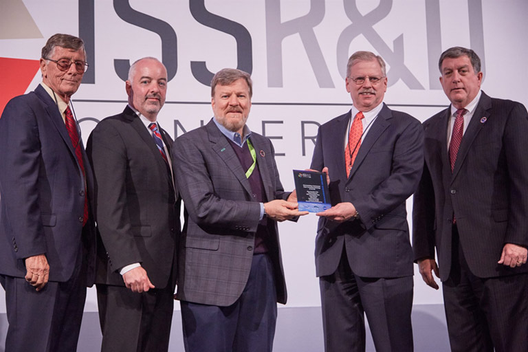 The HPE SBC 1 team received the 2018 ISS Innovation Award in Technology Development and Demonstration for the teams innovative work on SBC 1. Mark Fernandez (third from the left) and John Kichury (second from the right) of HPE accept the the award on behalf of the SBC 1 team.