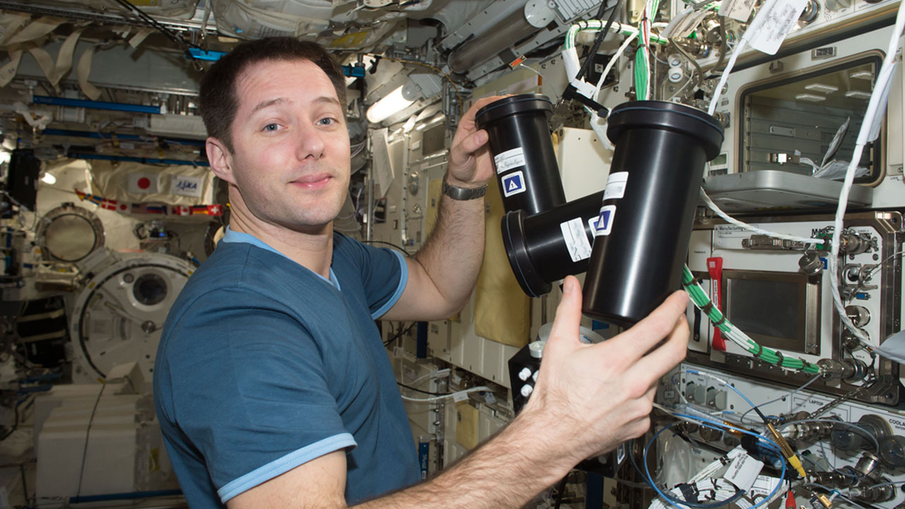 merck-pcg-thomas-pesquett ESA astronaut Thomas Pesquet removing the Protein Crystallization Facility hardware from the incubator on the ISS for Mercks investigation.