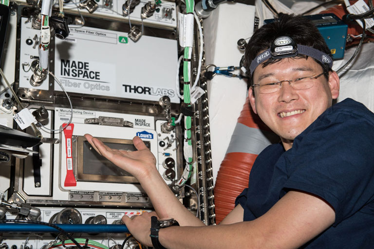 The MIS Optical Fiber Production in Microgravity (OFPIM) payload atop the Additive Manufacturing Facility with JAXA astronaut Norishige Kanai onboard the ISS.