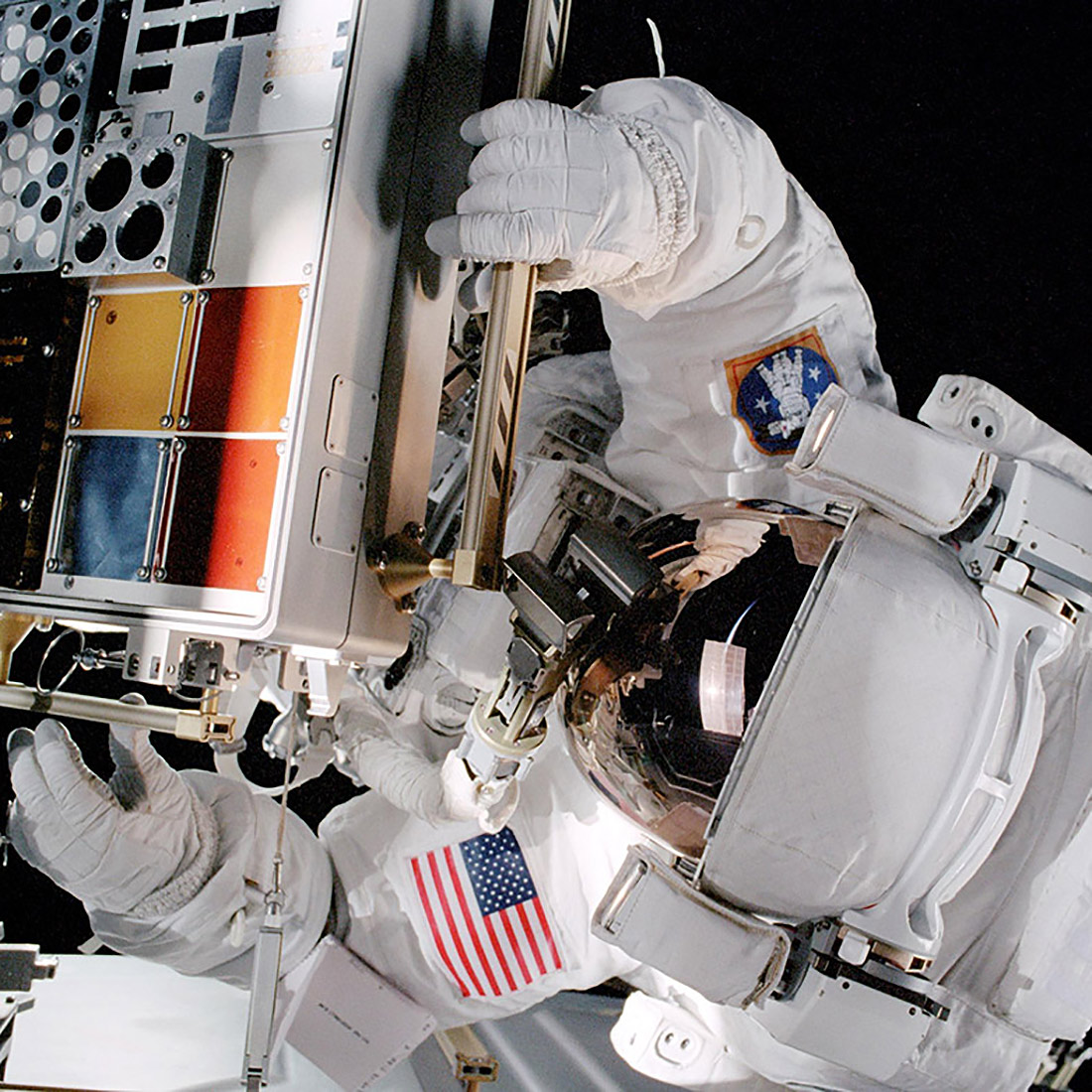 An astronaut installs a Materials International Space Station Experiment (MISSE) facility on the exterior of the ISS during a spacewalk in 2001. Future iterations of MISSE, handled by Alpha Space, will be installed and maintained via robotic arm, eliminating reliance on spacewalks.