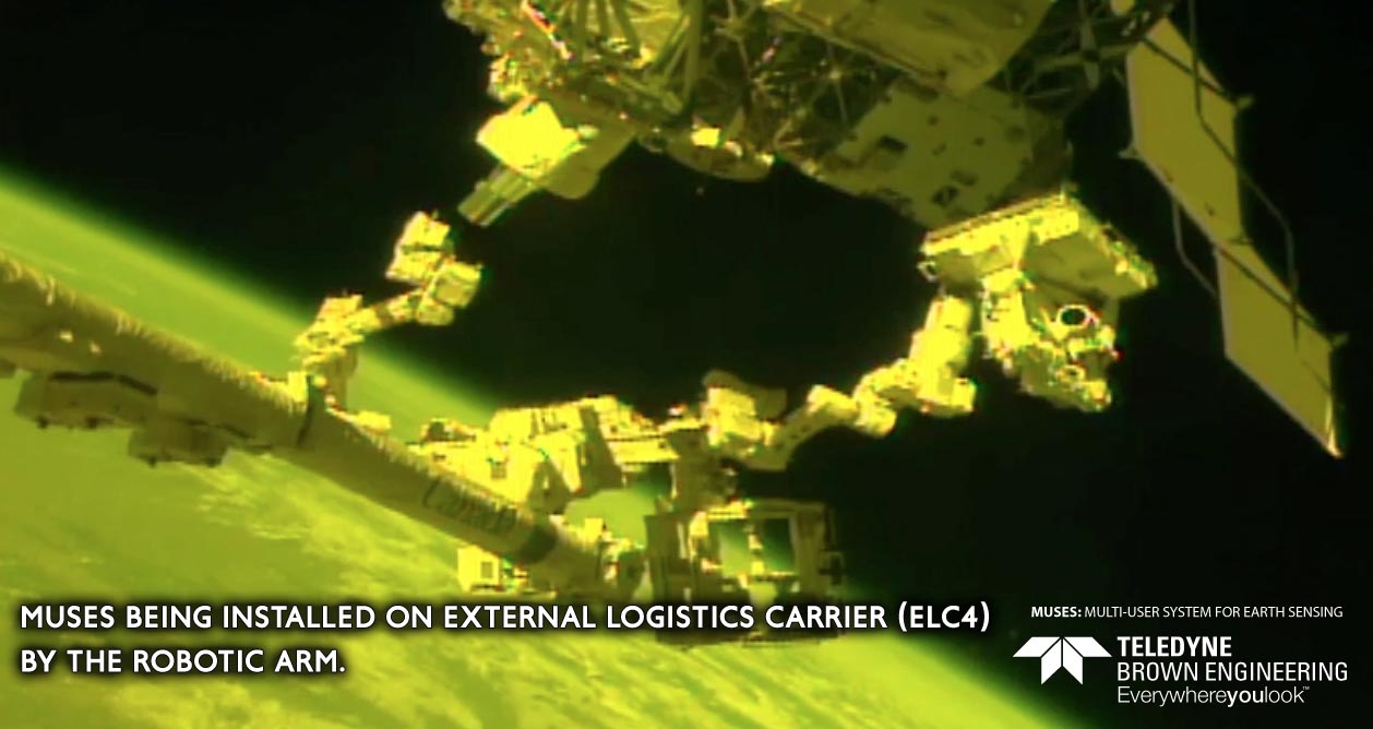 MUSES being installed on the External Logistics Carrier (ELC4) by the robotic arm.