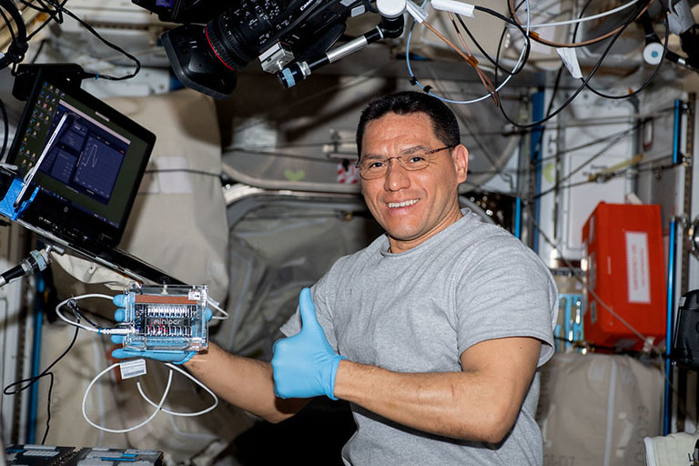 NASA astronaut Frank Rubio holds the Genes in Space miniPCR machine, which is used in many student investigations.