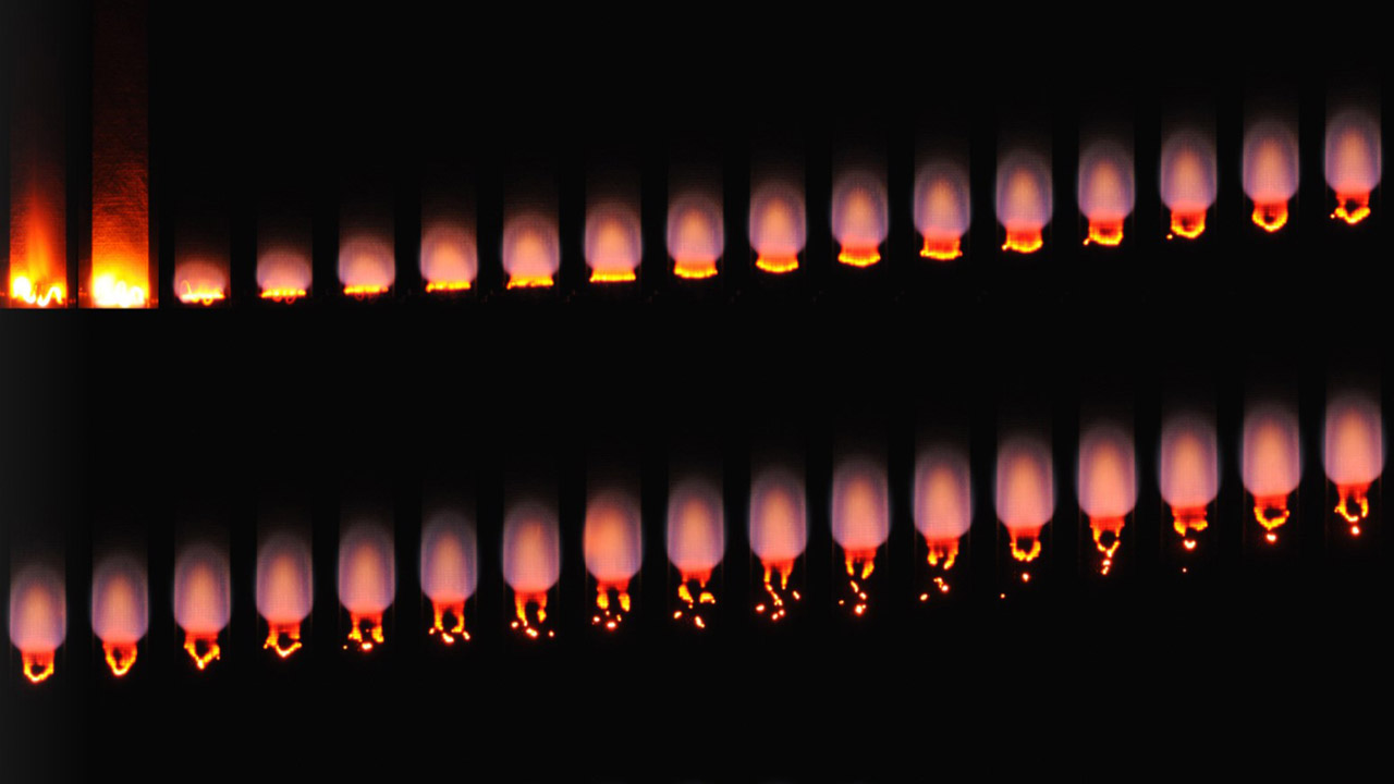 Montage of flame images for a burning 1 cm wide cotton blend fabric. Images are taken 1.125 seconds apart starting at the top and moving from left to right. Air flow speed is constant at 10 cm s, and flow direction is from bottom to top. The flame reaches steady state after about 10 seconds.