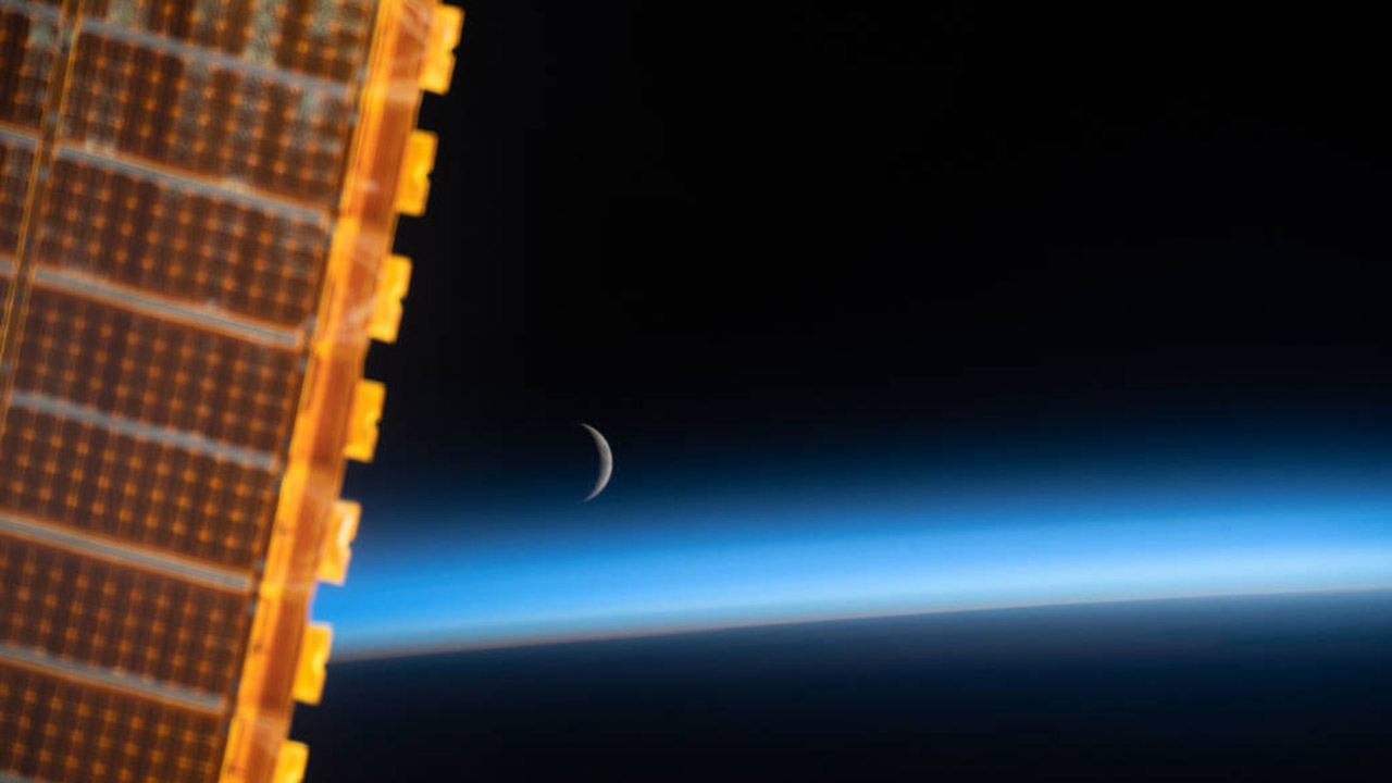 iss059e059211 (May 8, 2019) The waxing crescent moon is photographed just above Earths limb and the bluish hue of the atmosphere at the beginning of an orbital sunrise. A portion of one of the International Space Stations solar arrays is seen in the left foreground as the orbital complex flew 258 miles above the Sea of Japan.