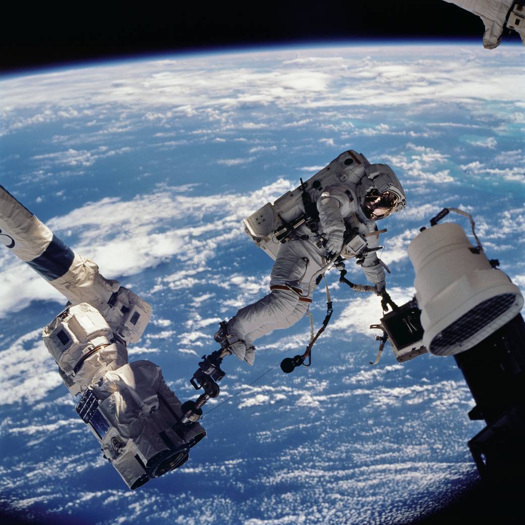Astronaut David A. Wolf, STS 112 mission specialist, anchored to a foot restraint on the Space Station Remote Manipulator System (SSRMS) or Canadarm2, carries the Starboard One (S1) outboard nadir external camera.