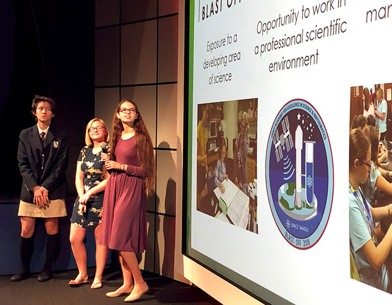Left to right: Emma Stone, Emma Grooms, and Raychel Kool presented their project to a public audience at the Kennedy Space Center Visitor Complex. Seven teams gave five minute presentations the morning of launch day.