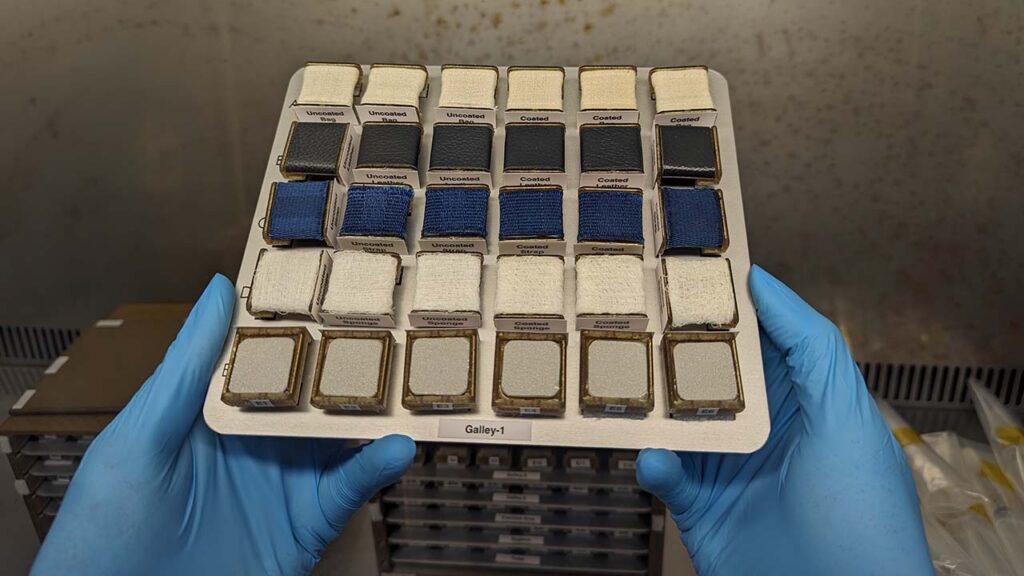 This aluminum placard contains various materials representative of spacecraft interior surfaces, with some surface samples coated in Boeings new antimicrobial coating.