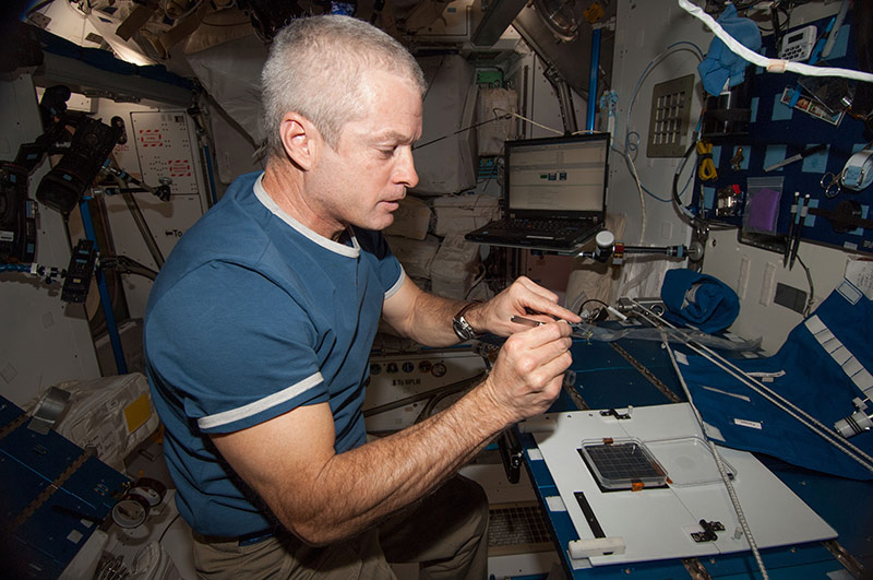 Astronaut Steve Swanson of NASA preparing the CARA imaging plate for use in the Light Microscopy Module (LMM) on the International Space Station.