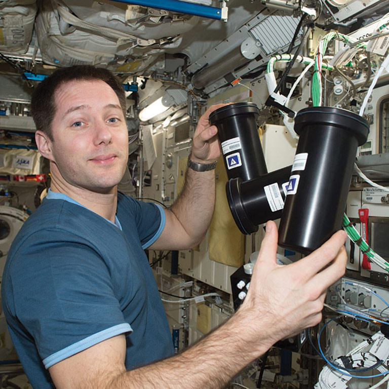 ISS crew member Thomas Pesquet removing the Protein Crystallization Facility hardware from the incubator on the ISS.