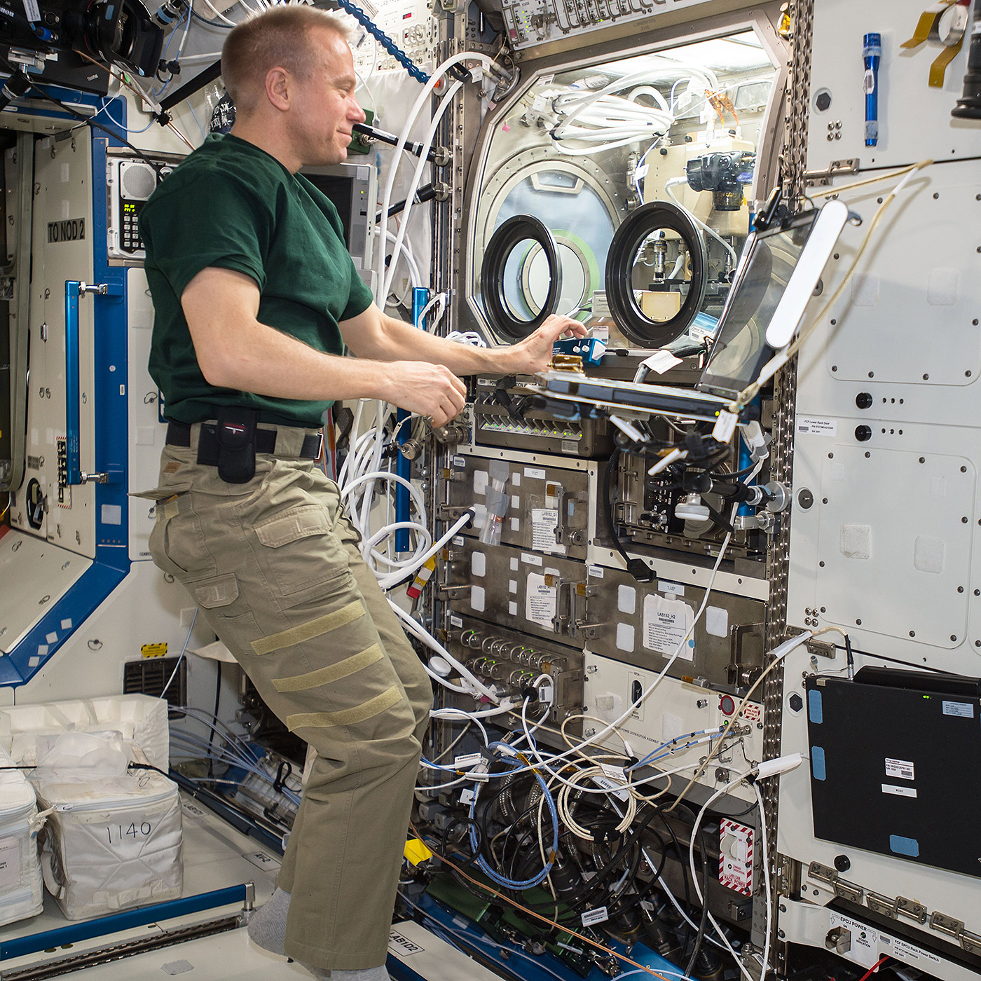NASA astronaut Tim Kopra sets up hardware for the Burning and Suppression of Solids  Milliken (BASS M) investigation, which will test flame retardant clothing against microgravity conditions. Results from the investigation will impact how flame retardant textiles will be used on Earth and in space.