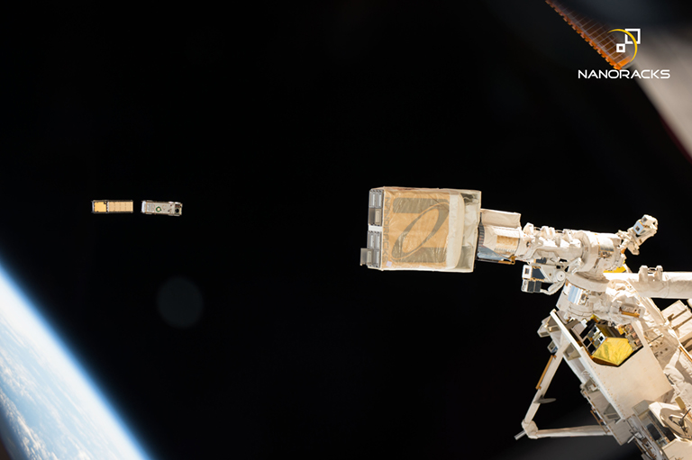 A pair of CubeSats being deployed from the NanoRacks CubeSat Deployer on the ISS