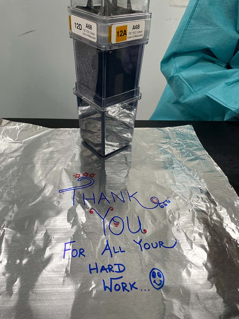 One of the custom cotton growth chambers sits on a message for the ISS crew written on foil used to pack the experiment.
