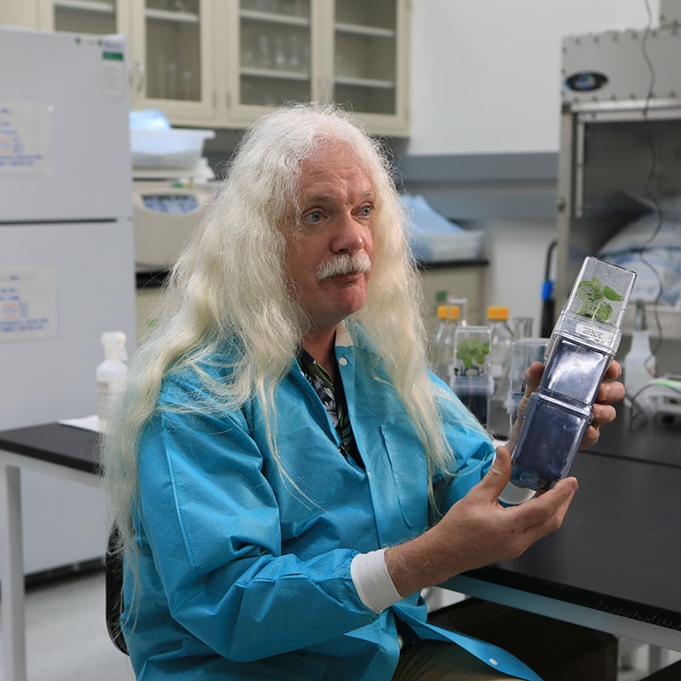 In a lab at Kennedy Space Center, Simon Gilroy holds one of several cotton growth chambers used for the teams experiment.