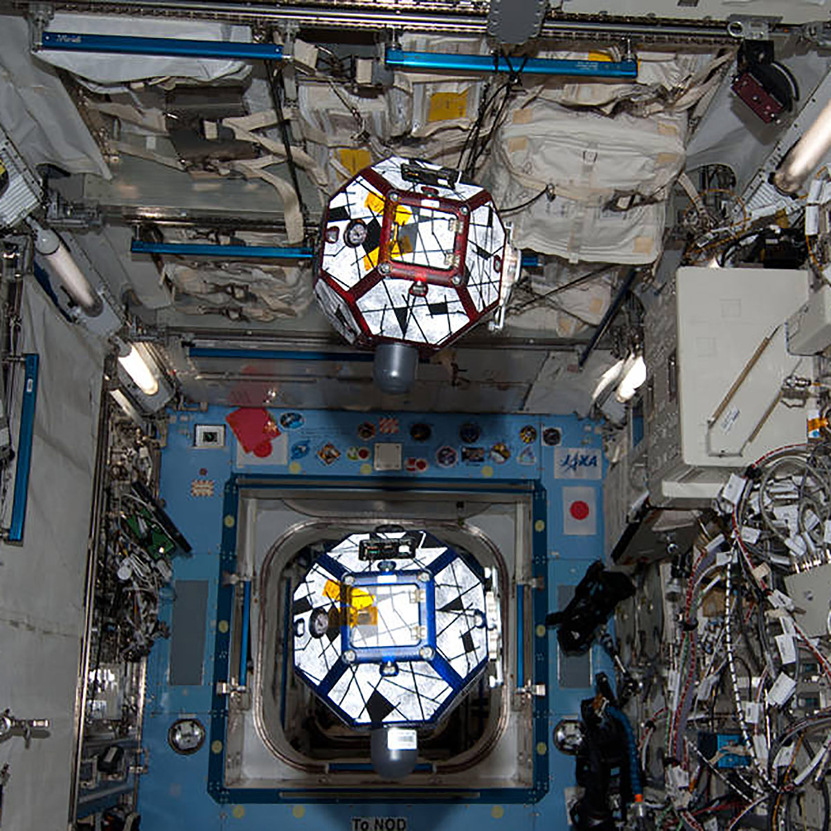 ISS036 E 003308(23 May 2013) Onboard the International Space Station, Expedition 36 Flight Engineer Chris Cassidy, NASA astronaut, watches from just out of frame as he devotes some time with the long running SPHERES experiment, also known as Synchronized Position Hold Engage and Reorient Experimental Satellites. The experiment is run in conjunction with students who program bowling ball sized satellites using algorithms. The free floating satellites are programmed to perform maneuvers potentially influencing the design of future missions.
