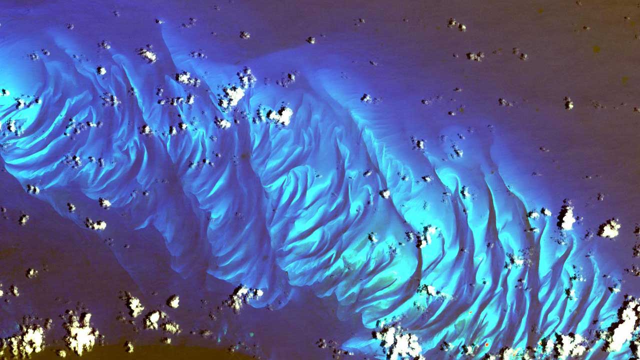 spectral-imaging-tarpum-bay-bahamas In this ASTER image the features that look like folded material are carbonate sand dunes in the shallow waters of Tarpum Bay, southwest of Eleuthera Island in the Bahamas.