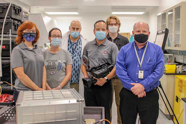 The team at Kennedy Space Center preparing the first experiment for launch on SpaceX CRS-21 in December 2020 (left to right: Siobhan Malany and Shelby Giza, of the University of Florida; Lee Malany, Mario Garcia, and Austin Hinkle of Micro-gRx; and Don Platt of Micro Aerospace Solutions).